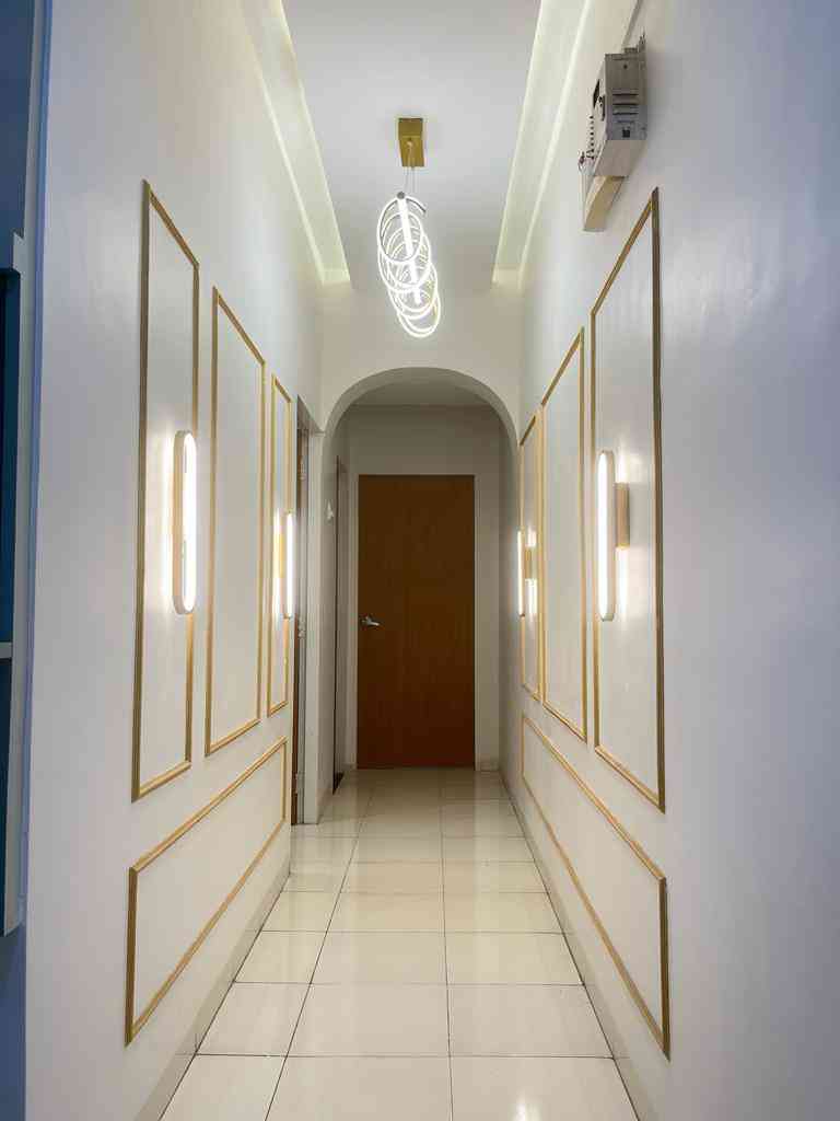 Elegant Hallway With Modern Lighting And Gold-Trimmed Wall Panels